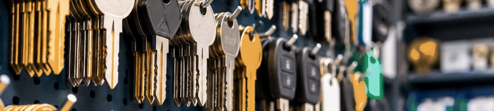A wall of keys hanging on pegboard above a locksmith's workbench